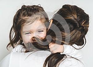 Mother comforting her crying little girl on white