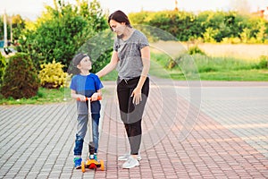 Mother comforting his son after crash. . Boy falls during learning to ride scooter. Safety, sports, leisure with kids