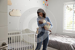 Mother Comforting Newborn Baby Son In Nursery