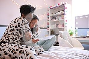 Mother Comforting Teenage Daughter In Bedroom Looking At Letter With Disappointing Exam Results 