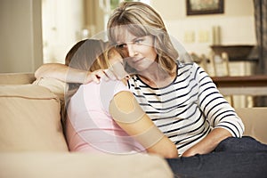 Mother Comforting Teenage Daughter Sitting On Sofa At Home