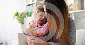 Mother consoles crying baby girl home closeup