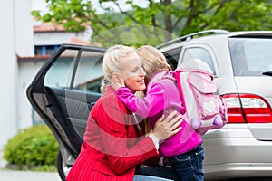 Mother consoling daughter on first day at school