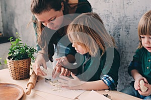 Mother cooking with kids in kitchen. Toddler siblings baking together and playing with pastry at home