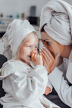Mother covering mouth while telling secret