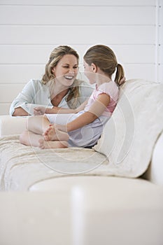 Mother Crouching Next To Girl Sitting On Sofa