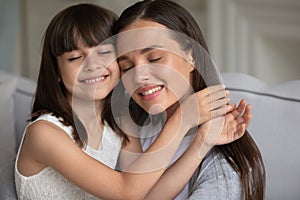 Mother cuddle daughter people with closed eyes enjoy tender moment