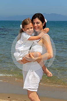 Mother cuddling daughter on a beach photo