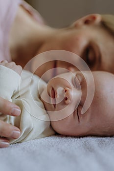 Mother cuddling with her newborn baby in their bad.