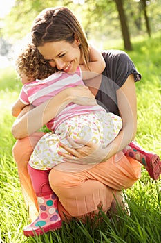 Mother Cuddling Young Daughter In Summer Field