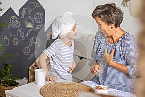 Mother and cute baby boy cooking food at childish kitchen playing chef educational playthings