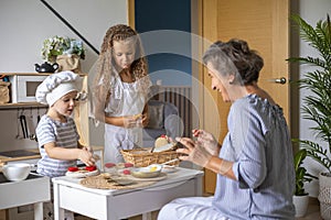 Mother and cute baby boy and girl cooking food at childish kitchen playing chef educational playthings