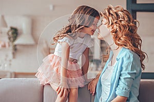 Mother and cute daughter touching nose to nose at home