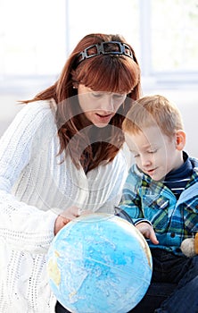 Mother and cute kid studying globe together