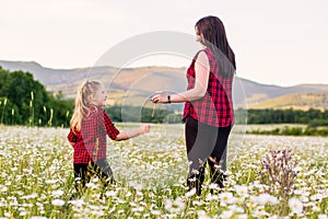 Mother with cute little child girl in the chamomile field