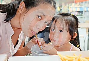 Mother and Cute little girl using straw to drink honeydew from plastic cup in cafe