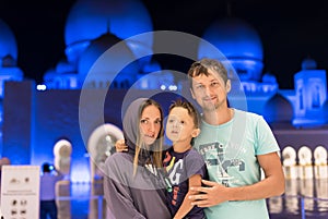 Mother with cute son and father dreaming at the grand mosque of Sheikh Zayed Mosque in Abu Dhabi wearing abaya, paranja in night t