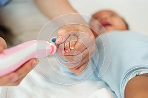 mother cutting baby's fingernails with auto electic nail trimmer