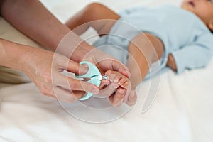 mother cutting baby's foot fingernails with nail scissors