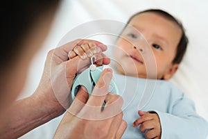 mother cutting baby\'s hand fingernails with nail scissors