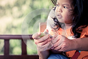 Mother cutting fingernails for her baby on green background