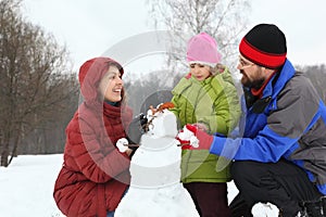 Mother and dad with daughter sculpt snowman