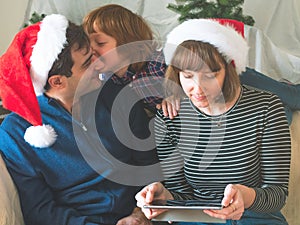 Mother, dad and son in santa caps on christmas holidays