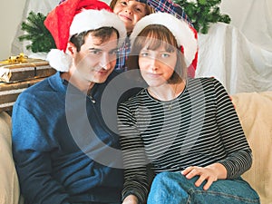 Mother, dad and son in santa caps on christmas holidays