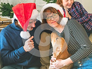 Mother, dad, son in santa caps and dog on christmas