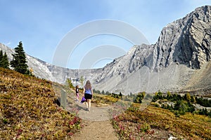 A mother and daugher hiking a beautiful trail above the treeline with a huge mountain in the background during a sunny fall day