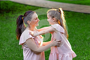 Mother and daughter 5-6 years old walking in the Park in the summer, daughter and mother laughing on a bench, the concept of a