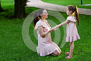 Mother and daughter 5-6 years old walking in the Park in the summer, daughter and mother laughing on a bench, the concept of a