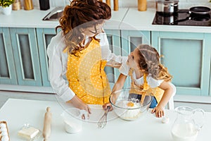 Mother and daughter in aprons looking at each other while cooking together