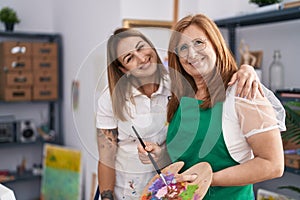 Mother and daughter artists hugging each other drawing at art studio