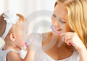 Mother and daughter baby girl brushing their teeth together