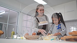 Mother and daughter is baking and cooking in home kitchen together for family fun activity concept.