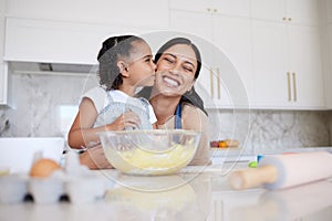 Mother and daughter baking together in a home kitchen. Caring small adorable little girl kissing her single mother on
