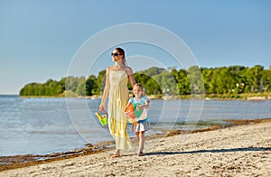 Mother and daughter with ball walking along beach