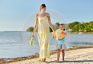 Mother and daughter with ball walking along beach