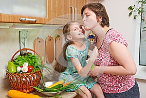 Mother and daughter with basket of vegetables and fresh fruits in kitchen interior. Parent and child. Healthy food concept