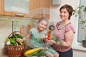 Mother and daughter with basket of vegetables and fresh fruits in kitchen interior. Parent and child. Healthy food concept