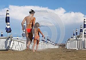 Mother and daughter in bathing suit going on beach