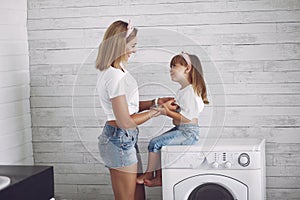 Mother and daughter in a bathroom near wash mashine