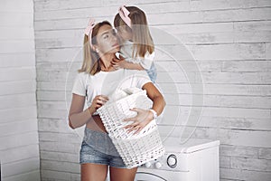 Mother and daughter in a bathroom near wash mashine