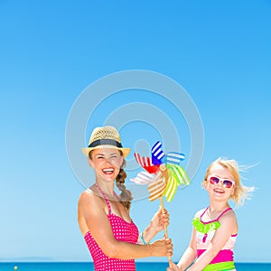 Mother and daughter on beach holding colorful windmill toy