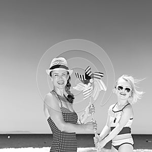 Mother and daughter on beach holding windmill toy