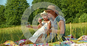 Mother and daughter blow soap bubbles in the park.