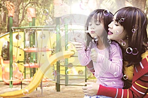 Mother and daughter blowing soap bubbles at park
