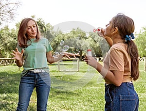 Mother and daughter blowing soap bubbles in a park