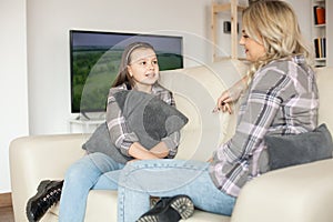 Mother and daughter boding while sitting on the couch